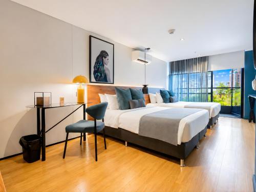 a bedroom with two beds and a desk in it at Hashtag 98 Hotel By Jalo in Medellín