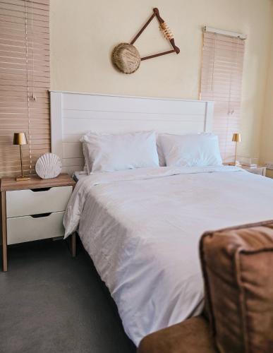 a bedroom with a white bed and a clock on the wall at Orang Cottages BW in Ramotswa