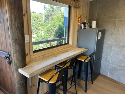 a kitchen with a counter with chairs and a window at Cabañas y Lodges de Playa Ritoque RITOKAZO in Quintero