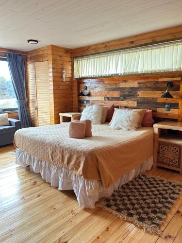 a bedroom with a large bed with a wooden wall at PEZ HOUSE in Pichilemu