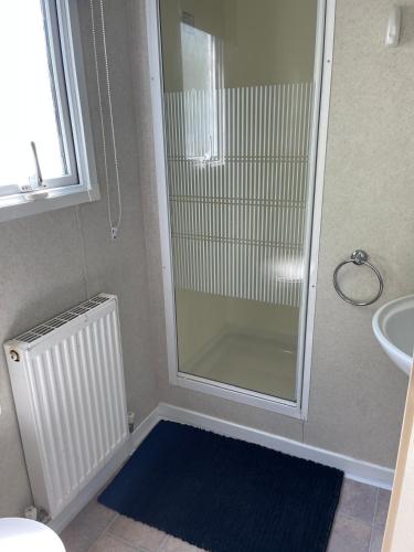 a bathroom with a shower and a blue rug at Holiday home / Caravan in Felpham