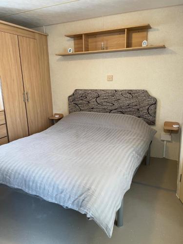 a bedroom with a bed with a white comforter at Holiday home / Caravan in Felpham