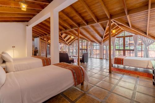 a bedroom with two beds in a room with wooden ceilings at Hospedaje Chaska Pisac in Pisac