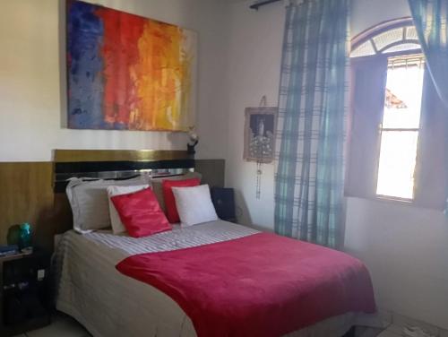 a bedroom with a bed with a red blanket at Férias pé na areia, sol e mar in Serra