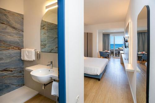 a hotel room with a sink and a bedroom at Hotel & SPA Riviera Castelsardo in Castelsardo