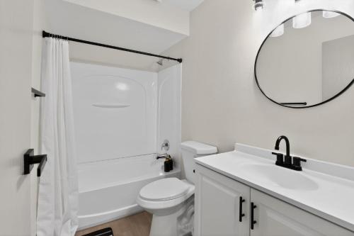 a white bathroom with a toilet and a mirror at Spacious 2BR stay with updated interiors in Lenexa