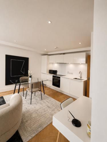 a kitchen and living room with white cabinets and a table at Parkway House in Chelmsford