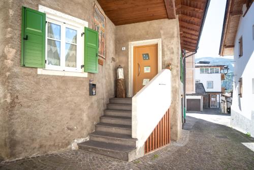 a staircase leading up to a building with green shutters at Casa vacanze Maria in Tesero