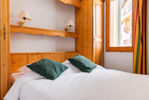 a bedroom with a bed with two green pillows at travelski home select - Résidence Les Chalets du Galibier 4 - 2 pièces 4 personnes in Valloire