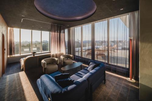 a living room with a blue couch and a large window at THE TSUBAKIMORI Hotel & Residence in Chiba