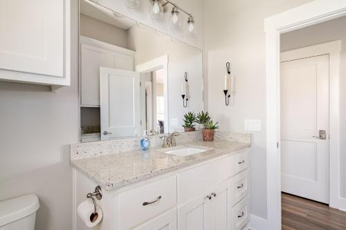 a white bathroom with a sink and a mirror at King Bed, Beach Views, The Salt Surf Shack in Bolivar Peninsula