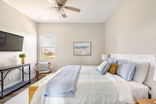 a white bedroom with a bed and a ceiling fan at King Bed, Beach Views, The Salt Surf Shack in Bolivar Peninsula