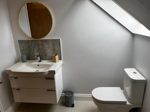 a bathroom with a sink and a toilet and a mirror at The loft in Tingewick