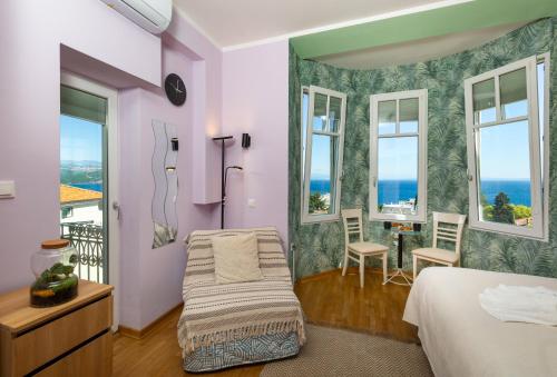 a bedroom with a bed and a chair and windows at Blue Horizon Studio Opatija in Opatija