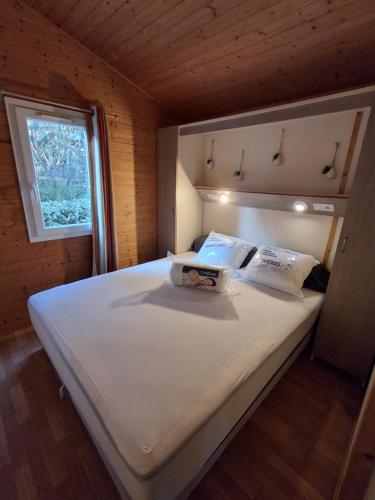 a large white bed in a room with a window at Chalet climatisé 6 personnes in Agde