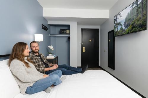 a man and woman sitting on a bed watching tv at OYO Times Square in New York