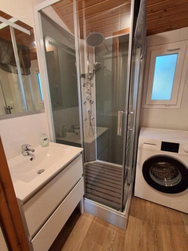 a bathroom with a shower and a washing machine at Chalet climatisé 6 personnes in Agde