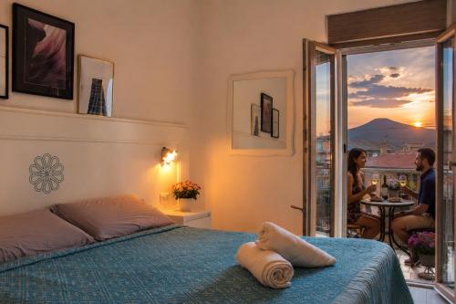 a bedroom with a bed and a woman sitting at a table at INAH Rooms in Dorgali