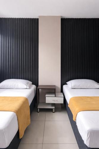a bedroom with two beds and a nightstand between them at Hotel Escorial Ibagué in Ibagué