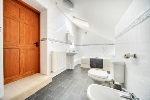 a bathroom with two toilets and a wooden door at Converted Barn - Super King beds, Parking, WiFi in Hockwold cum Wilton