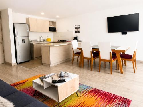 a living room with a kitchen and a table and chairs at Comodo Apto Diagonal MALL PLAZA in Manizales