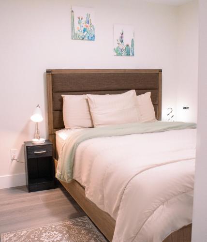 a bedroom with a bed with white sheets and a lamp at Modern Private 2-Bedroom Styld, Spacious & Comfy-Modern New 2-Bedroom Stylish, Spacious, Comfy & Nicely Furnished - Full Privacy in St. John's
