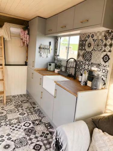 a kitchen with white cabinets and black and white tiles at The Stallion in Sturminster Newton