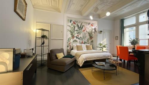 a bedroom with a bed and a couch and a chair at DUPLEX DE CHARME XVIIIᵉ - TERRASSE Privée - Centre Historique - HALLES GARE - Tout à Pied - RétroMirabeau Le Jacobin in Narbonne