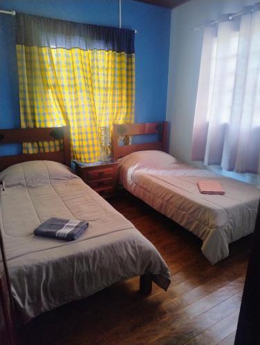 a bedroom with two beds and a yellow curtain at casa charme e praticidade in Campos do Jordão