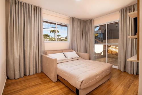 a living room with a couch and a large window at Pousada Sol da Mantiqueira in Campos do Jordão