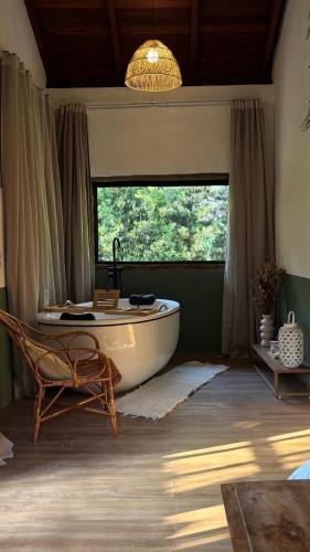 a bathroom with a tub and a chair and a window at Chalé na montanha com vista e lareira Mantiqueira in Costas