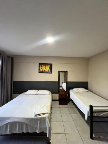a bedroom with two beds and a mirror at Ibiza Hostel Suites in Santa Cruz de la Sierra