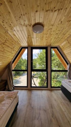 a room with two beds and large windows at Cabanele Infinyti in Colibiţa