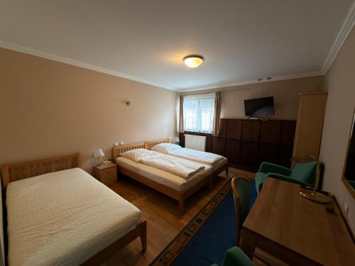 a room with two beds and a table and chairs at Gasthaus Goldener Anker in Gemünden