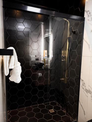 a bathroom with a black tiled shower with towels at Golden in Cochabamba