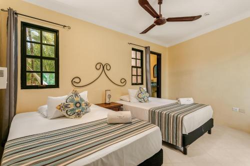 a bedroom with two beds and a ceiling fan at Hotel Barrio Latino in Playa del Carmen