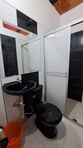 a bathroom with a black toilet and a sink at Hotel Rios in Garzón