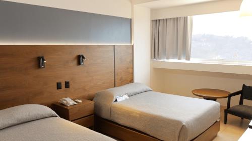 a hotel room with two beds and a window at Hotel Fortin Plaza in Oaxaca City