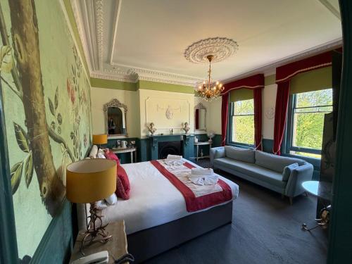 a bedroom with a bed and a couch and a chandelier at The Ayrlington Guesthouse in Bath