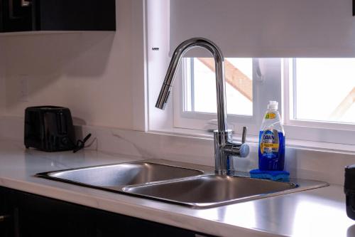 a kitchen sink with a bottle of detergent next to it at Modern Private 2-Bedroom Styld, Spacious & Comfy-Modern New 2-Bedroom Stylish, Spacious, Comfy & Nicely Furnished - Full Privacy in St. John's