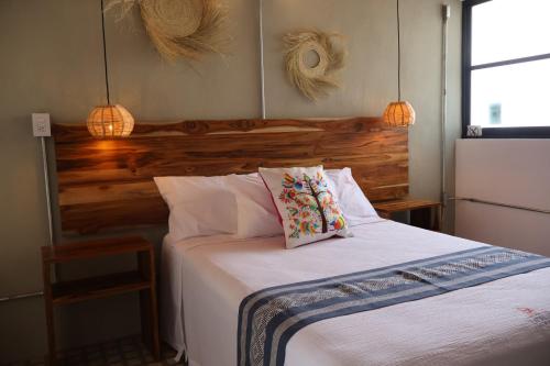 a bedroom with a white bed with a wooden headboard at Hotel Ladrillo in Oaxaca City