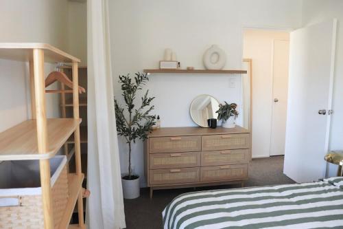 a bedroom with a bed and a dresser with a mirror at Central Nelson Townhouse in Nelson