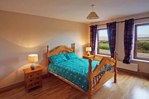 a bedroom with a wooden bed with a blue comforter at 4 Bed in Inch oc-i190 in Anascaul