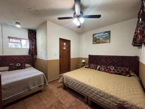 a bedroom with two beds and a ceiling fan at Hotel posada el paraíso in Tepoztlán