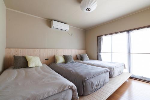 two beds in a room with a window at kobito in Toyama