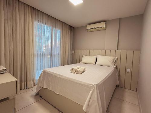 a bedroom with a bed with white sheets and a window at Villas de Samoa - House with 4 bedrooms in Cabedelo
