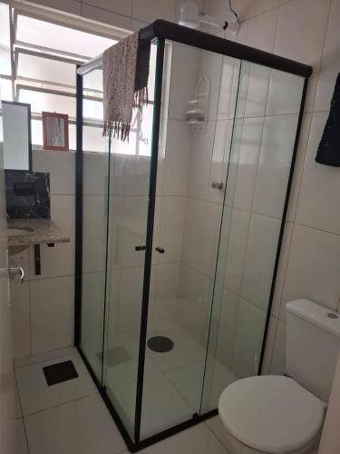 a glass shower in a bathroom with a toilet at Casa aconchegante in Peruíbe