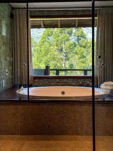 a bath tub in a bathroom with a large window at Estalagem Mandeville in Monte Verde
