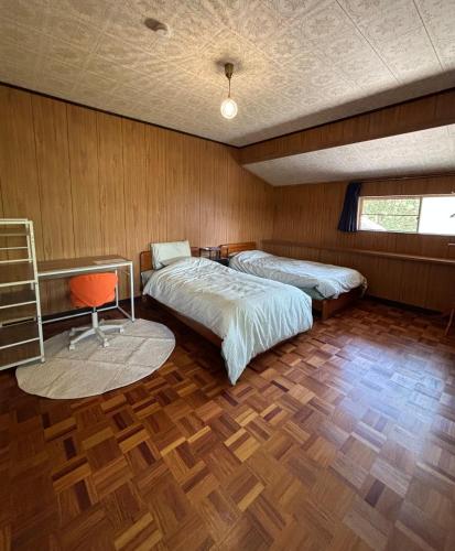 a bedroom with two beds and a chair in it at Edo house in Shiigi