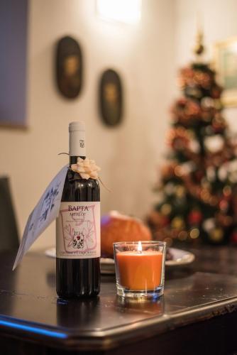 a bottle of wine and a candle on a table with a christmas tree at Vermaaten Boutique Suites Emerald in Todi